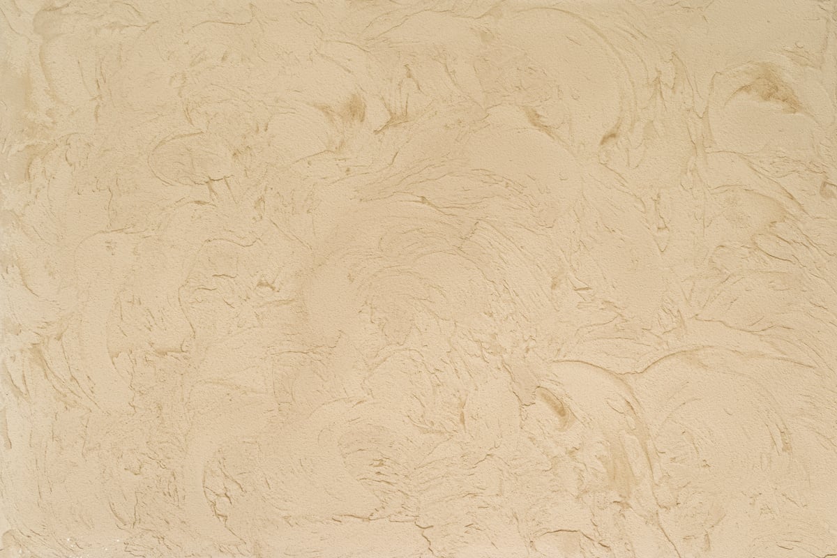 Abstract brush strokes patterns on champagne color plaster background.